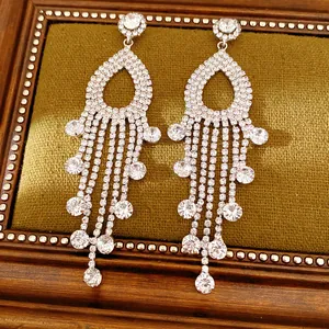 Primo piano di orecchini con nappe di strass su sfondo di velluto verde vintage