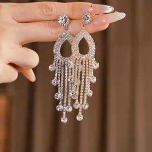 Primo piano di eleganti orecchini a nappa con strass e delicato design traforato