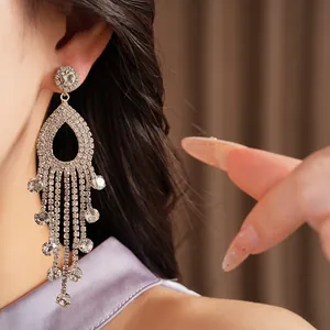 Dettaglio di eleganti orecchini pendenti a nappa con strass argentati indossati da modella
