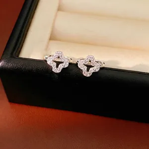 Elegant silver-toned hollow zircon clover hoop earrings displayed in a luxury box