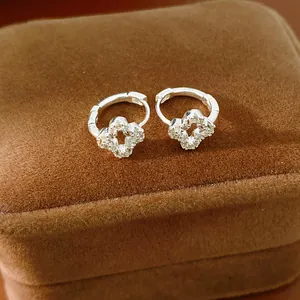 Close-up of elegant silver-tone clover hoop earrings with sparkling zircon stones.