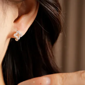 Macro detail of silver hollow clover earring encrusted with sparkling zircons