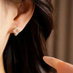 Close-up detail of an elegant hollow clover flower zircon ear buckle worn on a person's ear