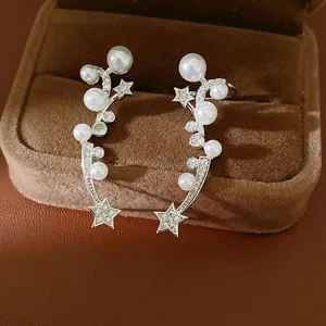 Macro view of elegant silver star and pearl ear clips on a brown velvet jewelry box