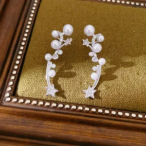 Close-up of elegant star and pearl clip-on earrings with cubic zirconia inlay on green velvet