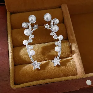 Close-up of elegant shooting star ear clips with white pearls and sparkling zircons