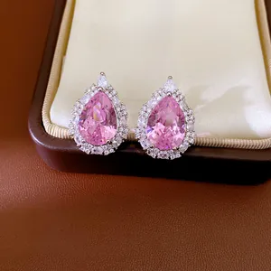 Detailed macro shot of elegant pink pear-cut zircon earrings in a luxury jewelry box.