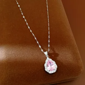 Close-up of elegant silver necklace with pear-shaped pink zircon and crystal halo