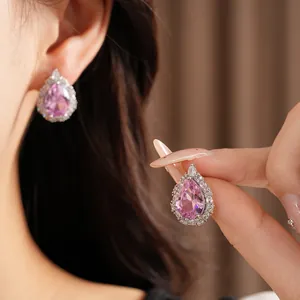 Detailed close-up of elegant pink pear-shaped zircon halo stud earrings on model