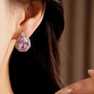 Macro detail view of an elegant pink pear-shaped zircon stud earring worn on ear