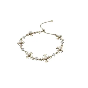Elegant French style gold-tone cross bracelet with pearls and rhinestones on white background.