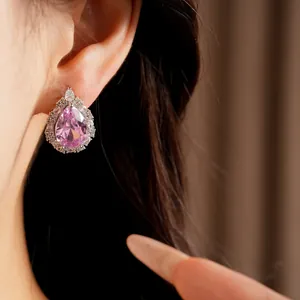 Macro detail of a pear-cut pink zircon earring with a sparkling clear halo setting.