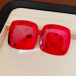 Elegant red square resin stud earrings with black marbled patterns in a display box