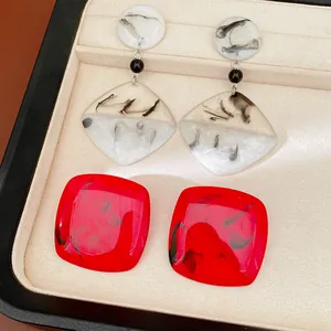 Close-up detail of resin square and drop earrings featuring artistic ink-wash marble patterns