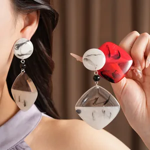 Macro view of elegant resin drop earrings with artistic ink-wash pattern on model