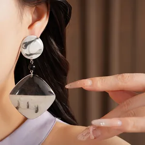 Close-up of a resin drop earring with black and white marbled ink-wash pattern on a model