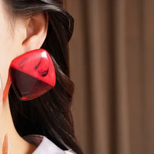 Close-up detail of red and black resin square ombre stud earring worn on model ear