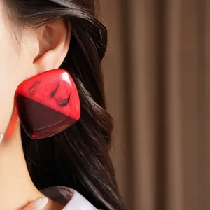 Detailed close-up showing large square red marbled resin earrings worn by a model