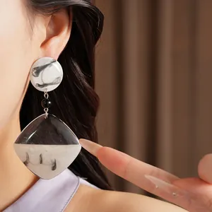 Detailed view of oversized marble-pattern resin earrings worn by a model