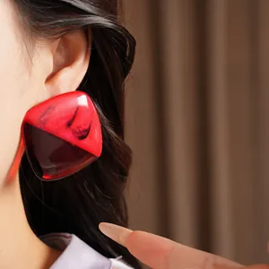 Macro view of square red marbled resin earring with silver post shown on a model's ear
