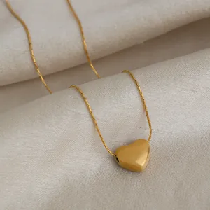 Gros plan élégant d'un pendentif cœur en or lisse sur une chaîne minimaliste en acier.
