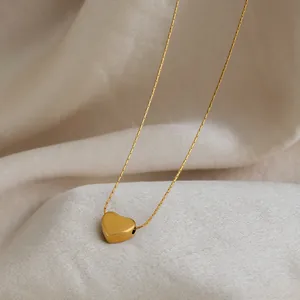 Gros plan sur la finition dorée lisse d'un pendentif cœur minimaliste de haute qualité
