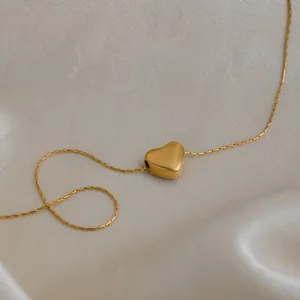 Gros plan d'un collier pendentif cœur en acier inoxydable doré 18 carats sur de la soie