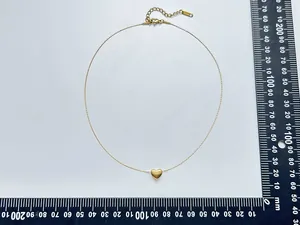 Vue détaillée de dessus d'un collier minimaliste en acier doré avec un pendentif en cœur