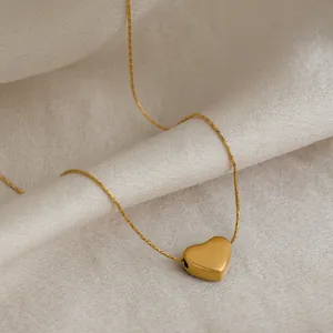 Gros plan d'un collier pendentif cœur en acier inoxydable doré 18 carats sur tissu