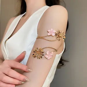 Detail eines goldenen Blumen-Armreifs mit rosa Emaille und goldenen Gänseblümchen am Arm