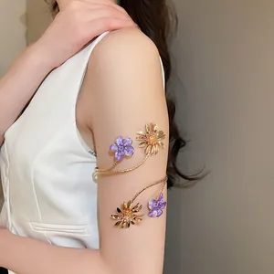 Nahaufnahme eines goldenen Oberarmreifs mit lila und goldfarbenen Emaille-Blumen