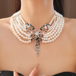 Dettaglio della collana di perle multistrato con ciondolo a farfalla in cristallo
