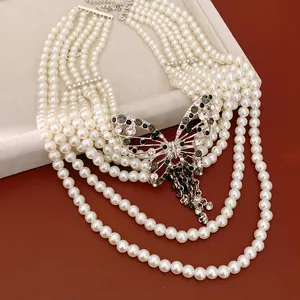 Vista dettagliata di una collana di perle multifilo con pendente a farfalla in strass.