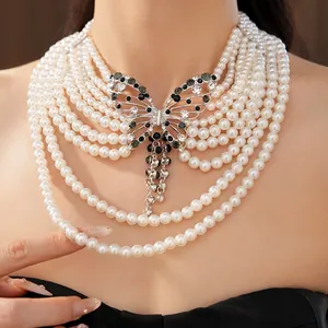 Primo piano di una collana di perle a più strati con ciondolo a farfalla con strass