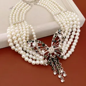 Dettaglio ravvicinato di collana di perle multifilo con pendente a farfalla di strass.