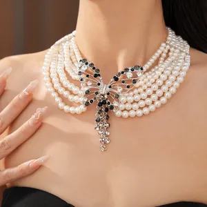 Dettaglio di una collana di perle a più strati con una farfalla traforata in strass