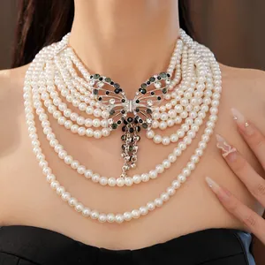 Dettaglio della collana di perle a strati con ciondolo a farfalla in strass