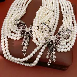 Dettaglio di collana di perle a più fili con eleganti ciondoli a farfalla in strass lucidi