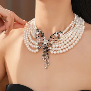 Dettaglio della collana di perle a più fili con ciondolo a farfalla di strass