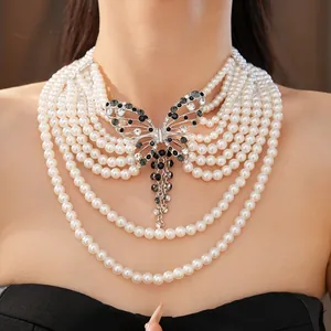 Dettaglio di una collana di perle multifilo con un grande pendente a farfalla di cristallo.