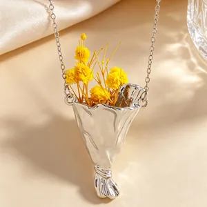 Macro del ciondolo a bouquet d'argento con trama metallica e fiori secchi di colore giallo