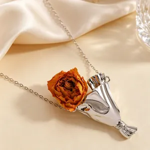 Macro della collana con ciondolo a bouquet argentato e vera rosa essiccata arancione
