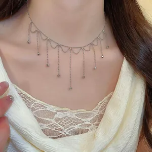 Detailed view of elegant silver metal tassel choker necklace on a model's neck, minimalist style