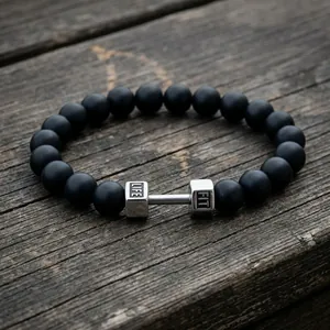 Macro shot of matte black onyx beads with a silver dumbbell charm engraved LIFE FIT