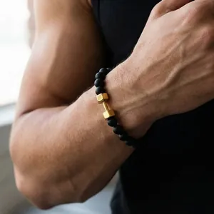 Detail of matte black onyx beads and a golden dumbbell charm on a men's fitness bracelet