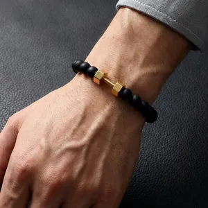 Close-up of men's black onyx bead bracelet with a golden dumbbell charm on wrist