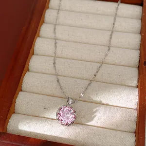 Gros plan d'un collier avec pendentif en zircone rose étincelant sur un plateau à bijoux.