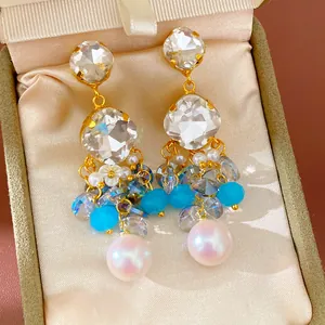 Close-up of luxury geometric glass earrings with pearls and blue crystal drops in a box