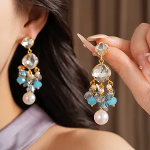 Detailed close-up of geometric glass tassel earrings with blue beads and white pearl