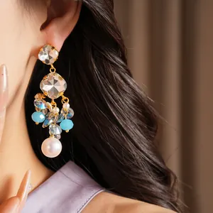 Detail view of geometric crystal earrings with colorful beads and white pearl drop